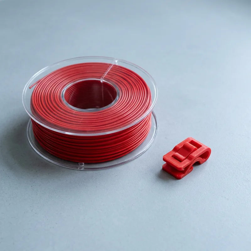 Signal-red ASA filament coil beside a printed automotive-style clip
